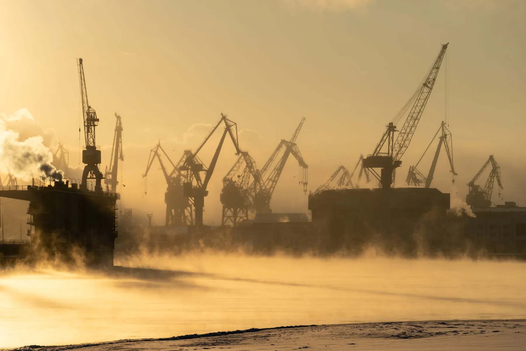 Shipyard cranes in morning sea mist (illustrative)